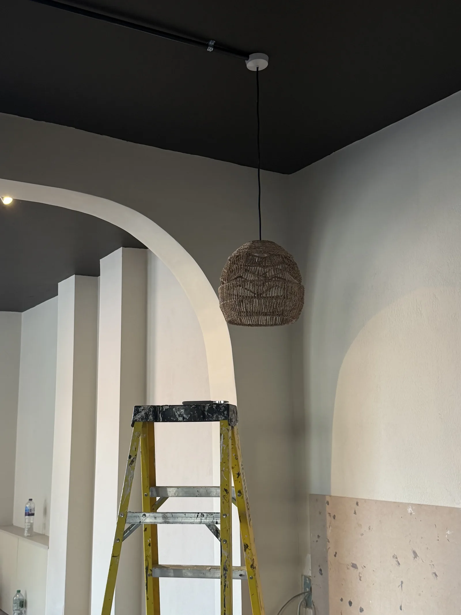 Victoria Street on site — a curved plastered opening beneath a black ceiling, with a woven pendant and a ladder in place